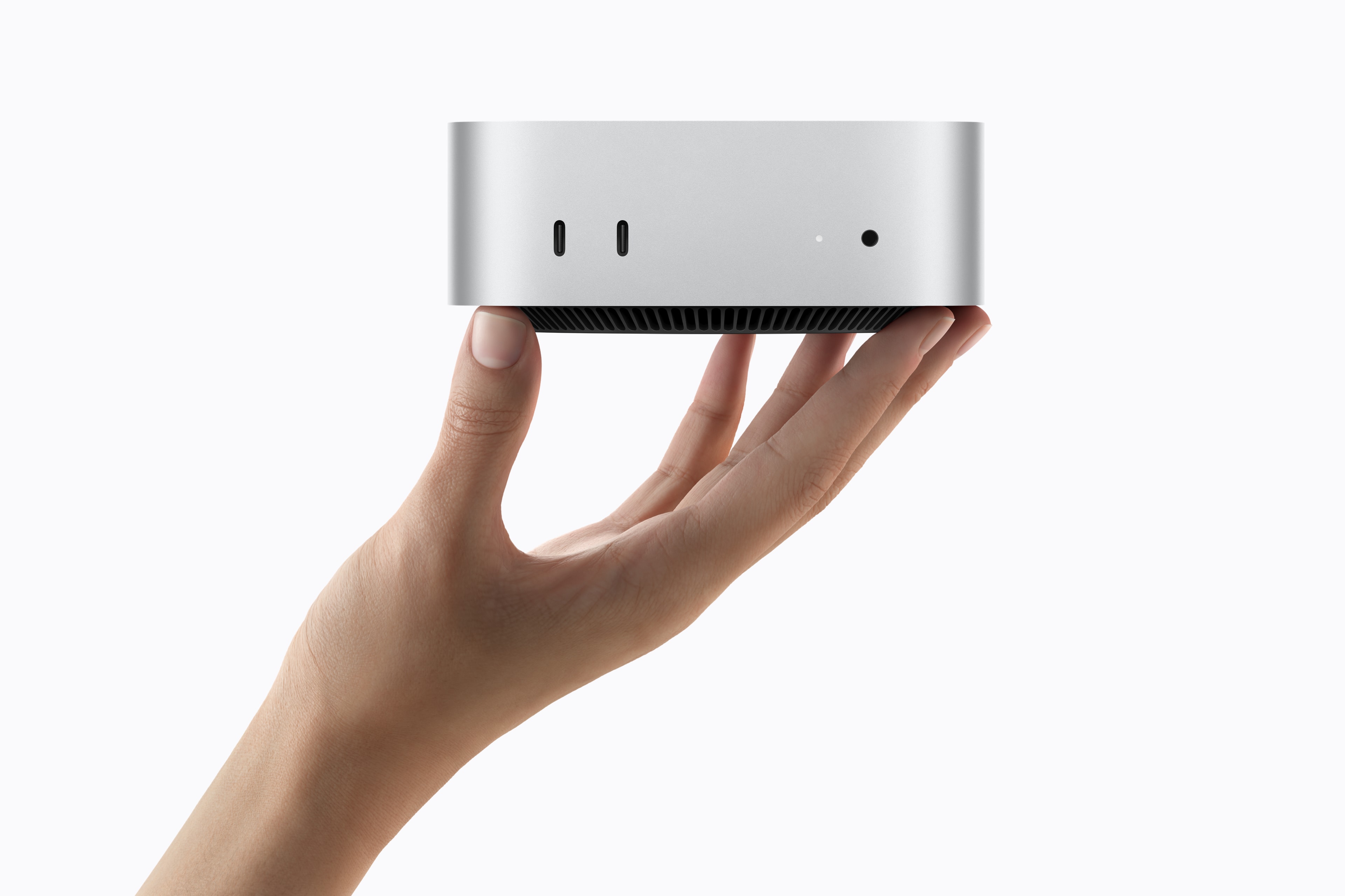 Fotografía oficial de Apple de una mano sosteniendo el Mac mini y mostrando sus puertos frontales
